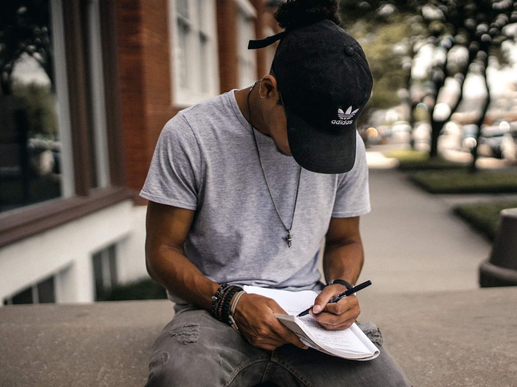 Imagem de um rapaz a escrever num caderno, ponderando as suas opções de carreira para o futuro.